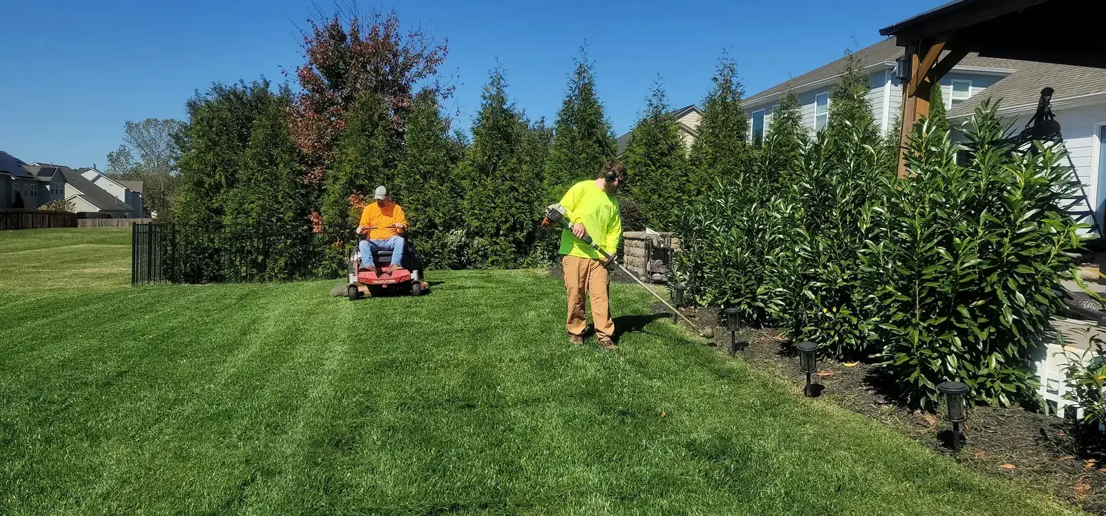 Jardinero cortando el césped de un jardín comunitario con cortacésped profesional
